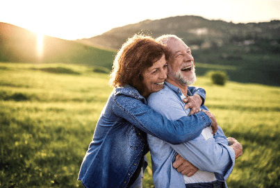 Older couple hugging and smiling in a field